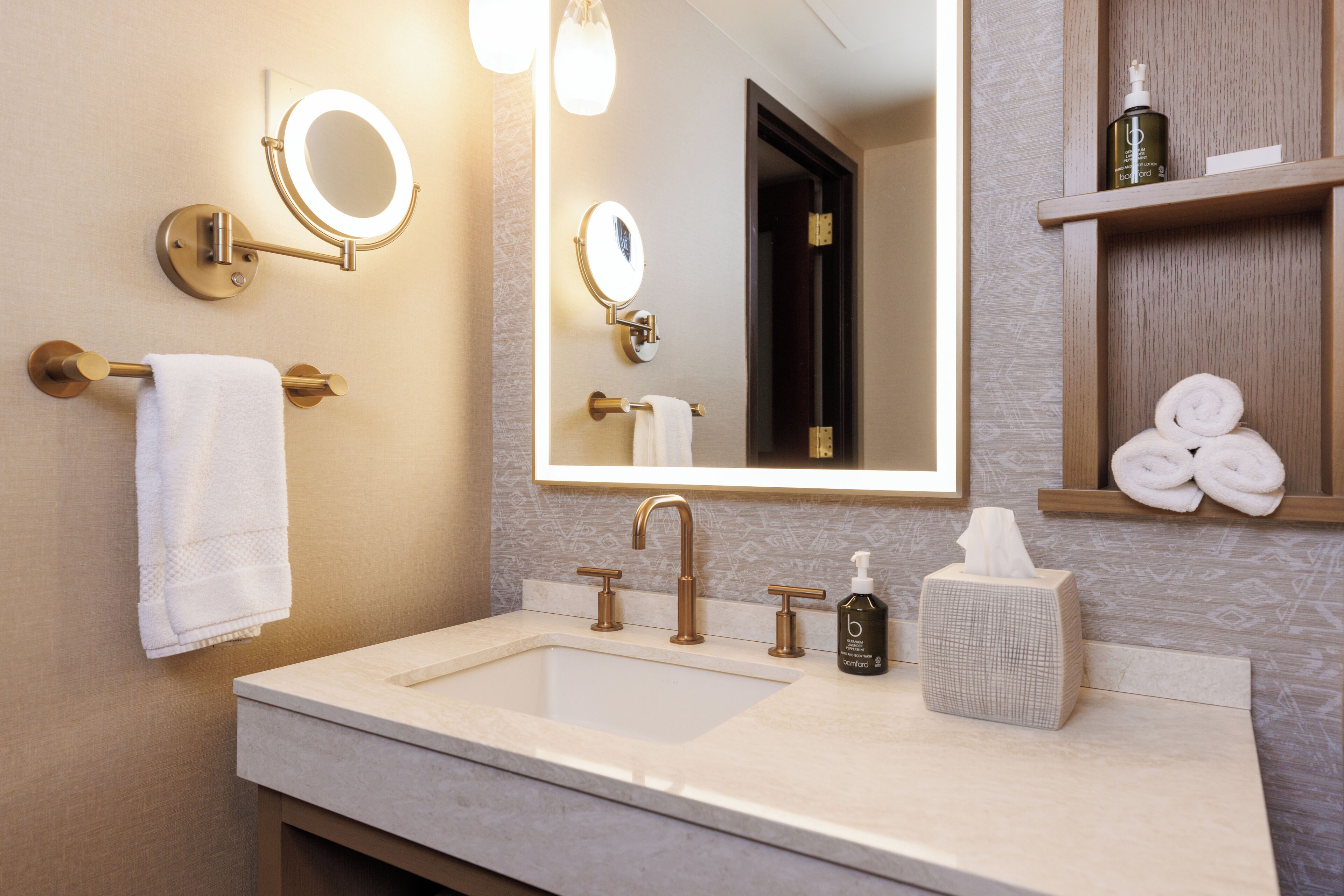 A modern bathroom with a large mirror, a sink, and a towel rack.