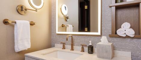 A modern bathroom with a large mirror, a sink, and a towel rack.