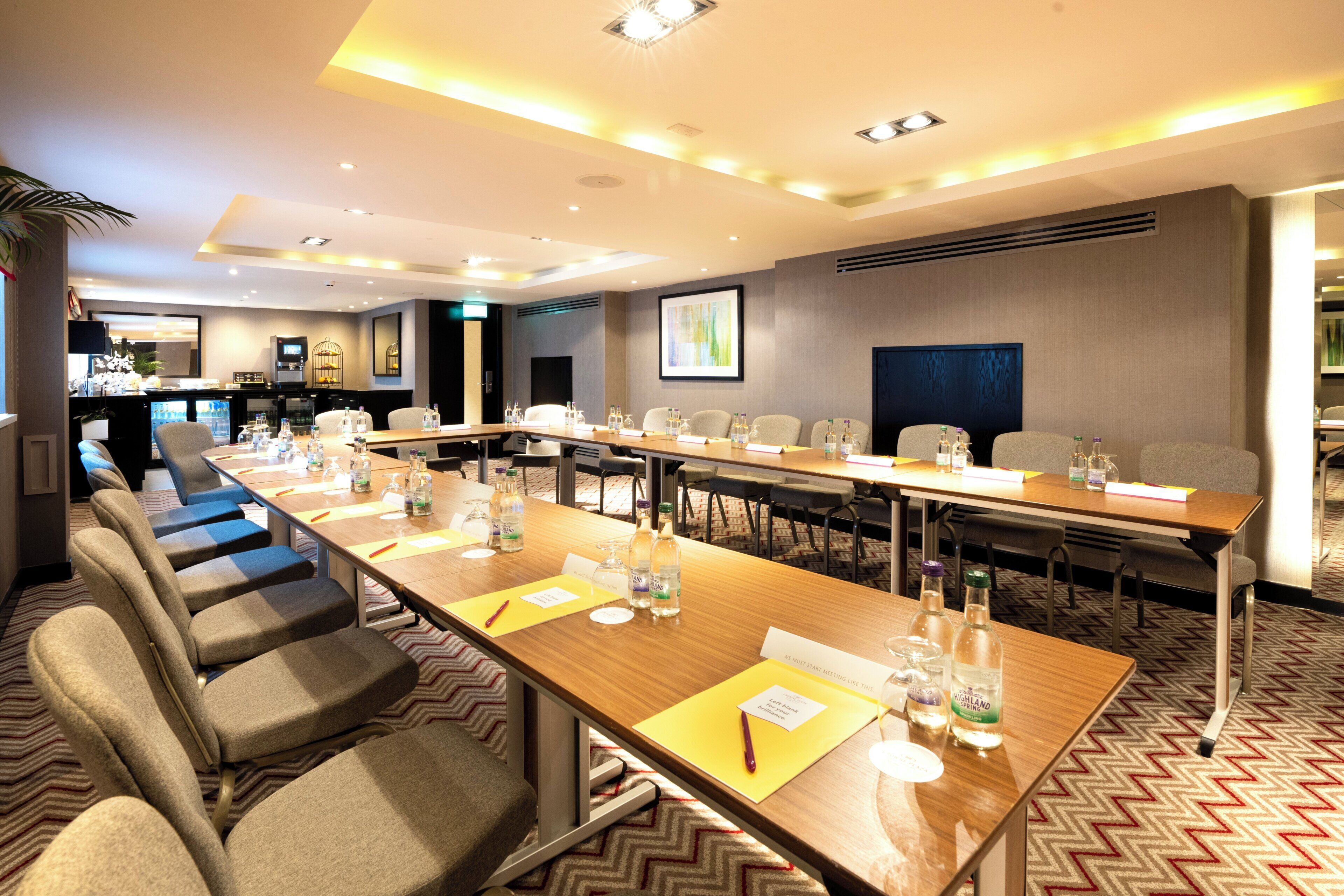 A conference room with a long table, multiple chairs, and a projector screen.