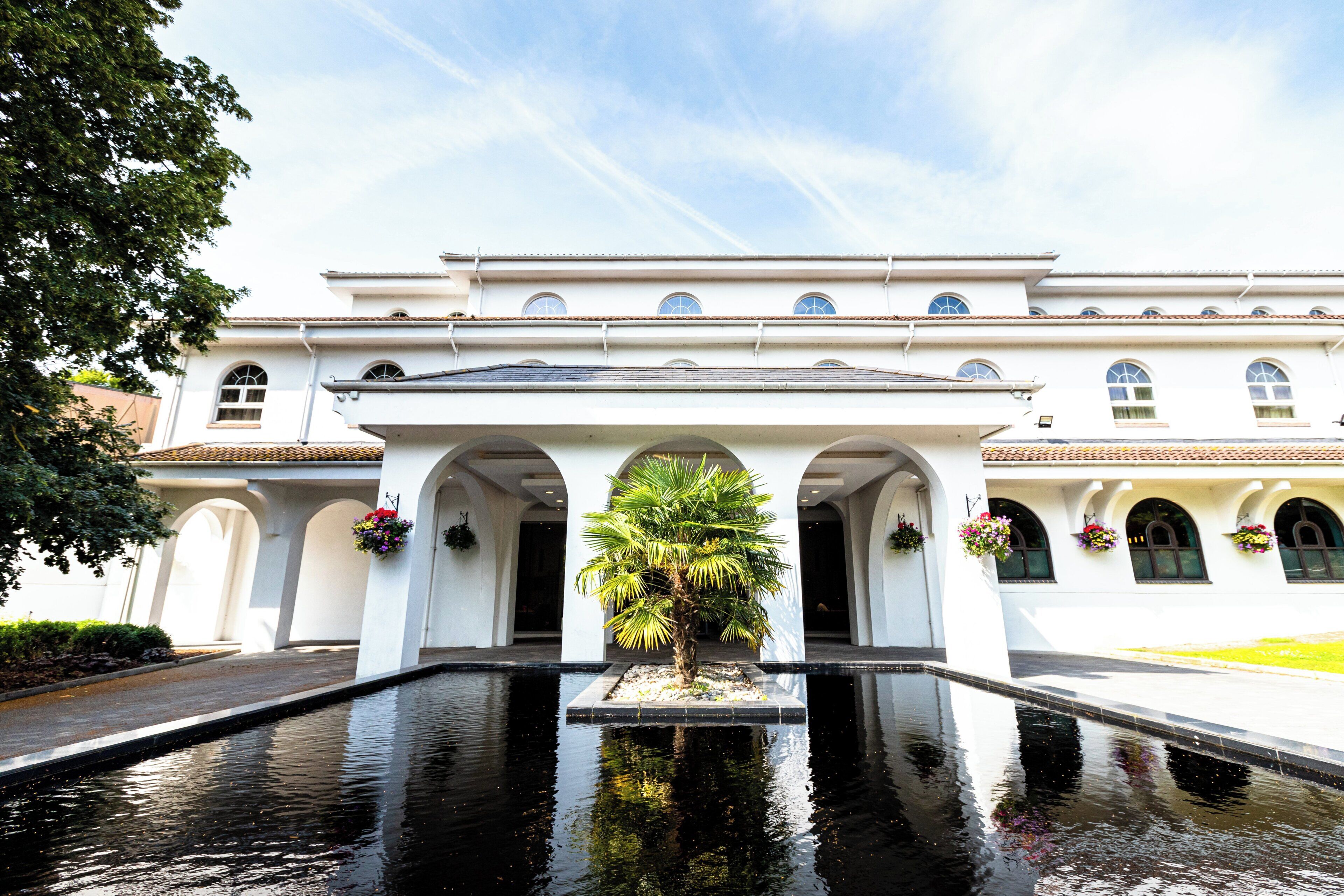 Un edificio blanco con un patio central, columnas de arco y una fuente.
