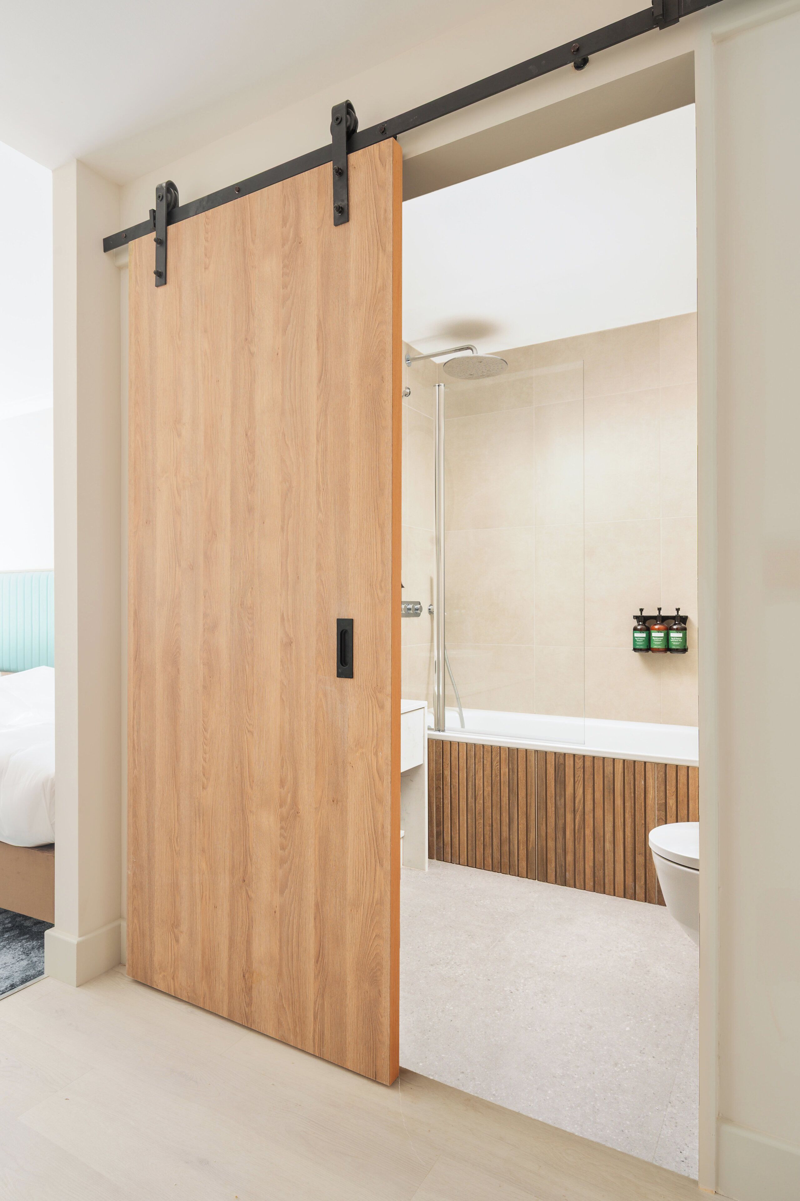 A modern bathroom with a wooden sliding door, a shower, and a toilet.