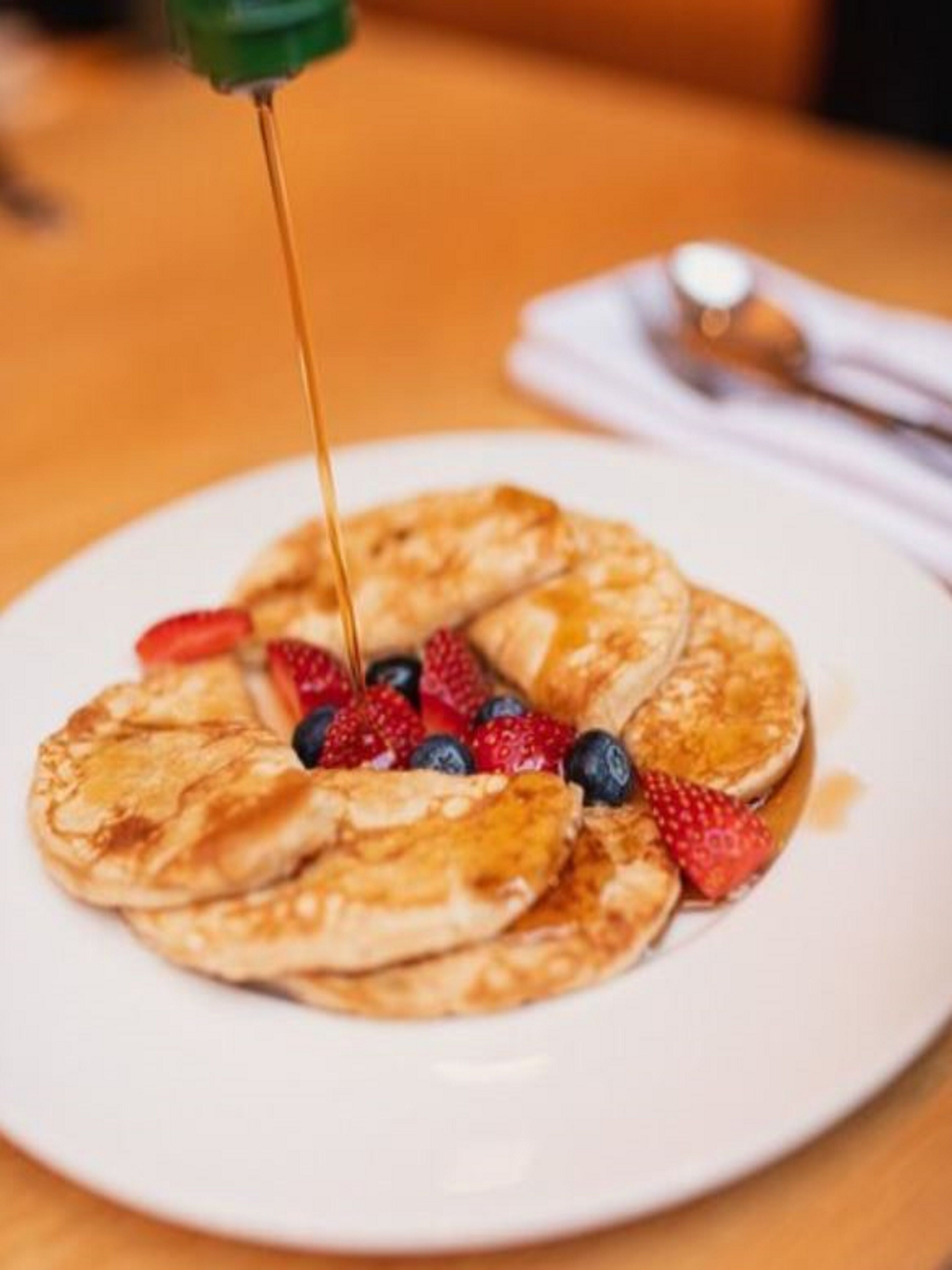 A plate of pancakes with syrup and berries.