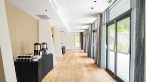 A hotel corridor with a long wooden floor, a reception desk with coffee makers, and large windows with curtains. - Crowne Plaza Gerrards Cross by IHG (Beaconsfield)