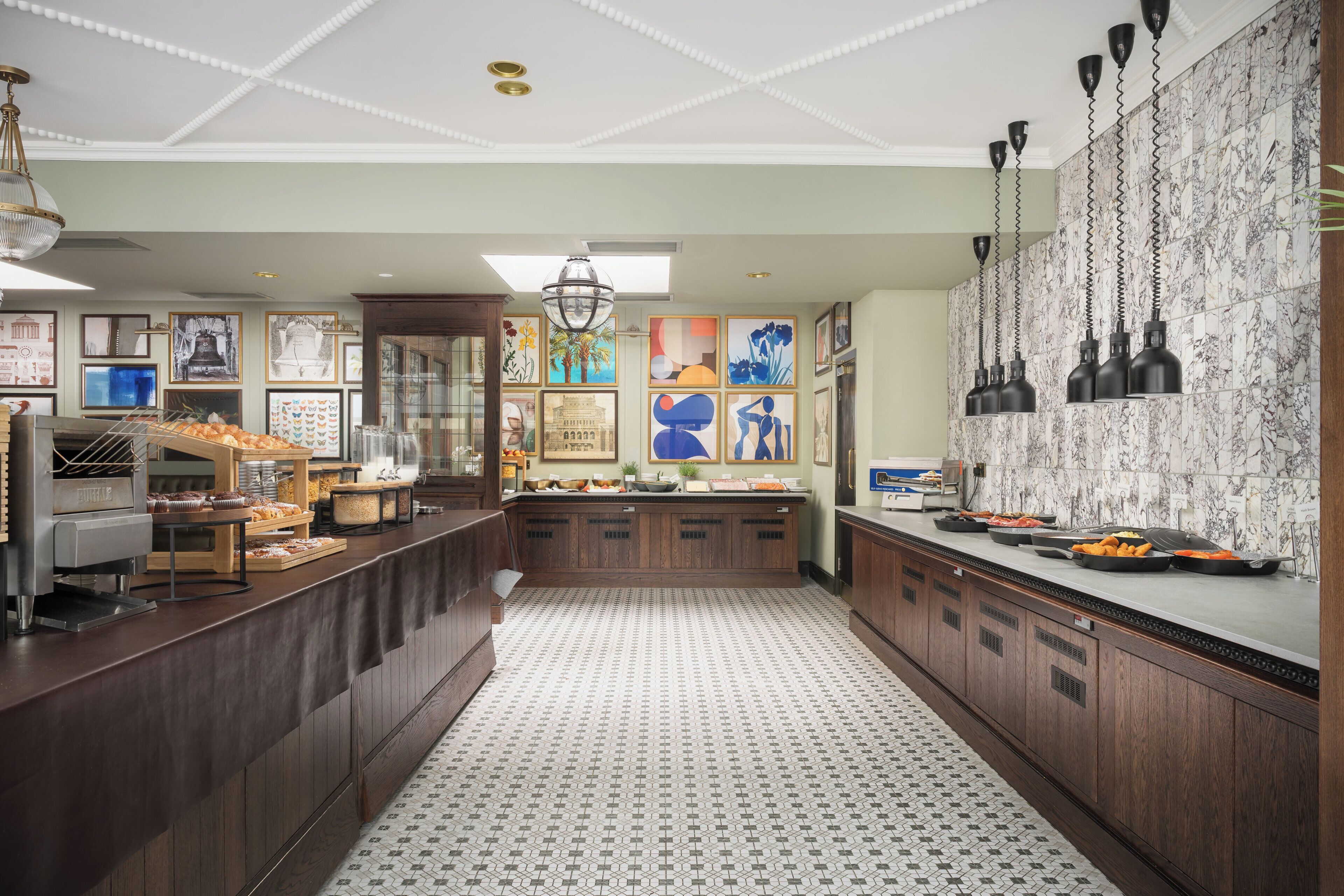 Una cocina amplia con armarios de madera, piso de baldosas y diversas exhibiciones de alimentos.