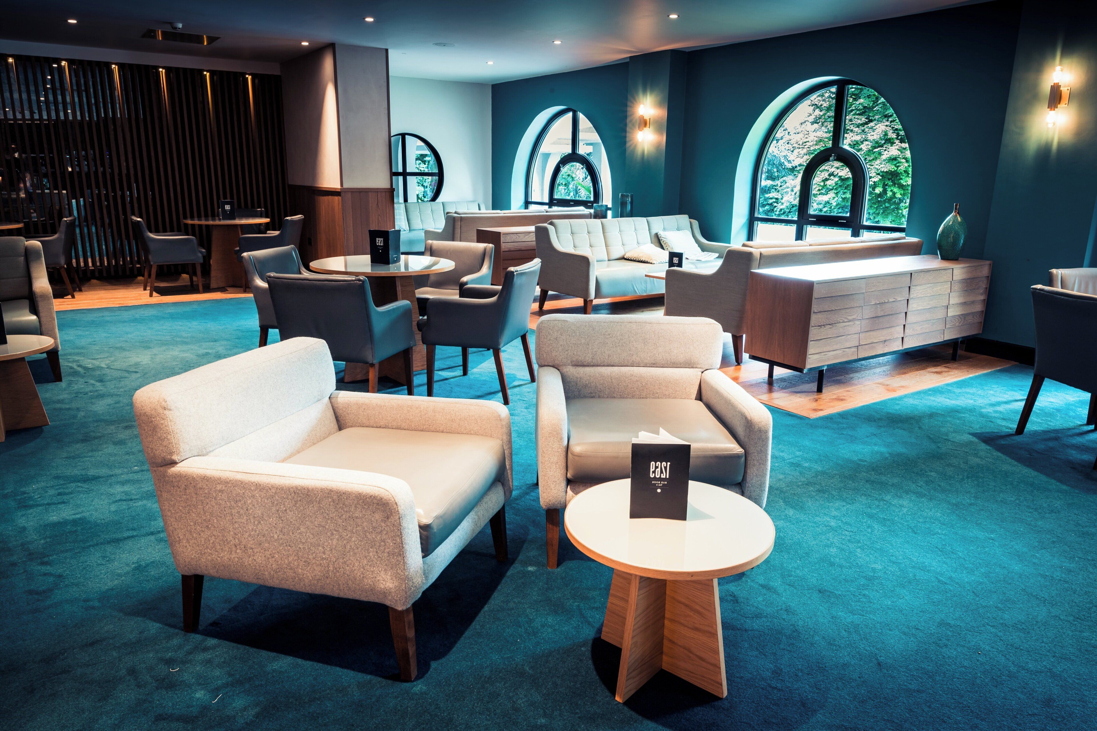 A modern lounge area with sofas, chairs, and a bar.