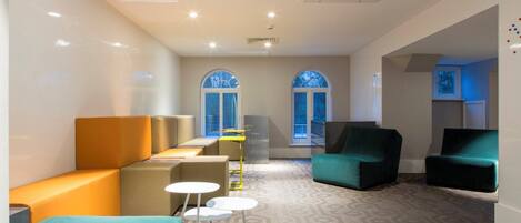 Ein stilvoller Lounge-Bereich mit Sitzmöbeln, einem gemusterten Teppich und großen Fenstern.