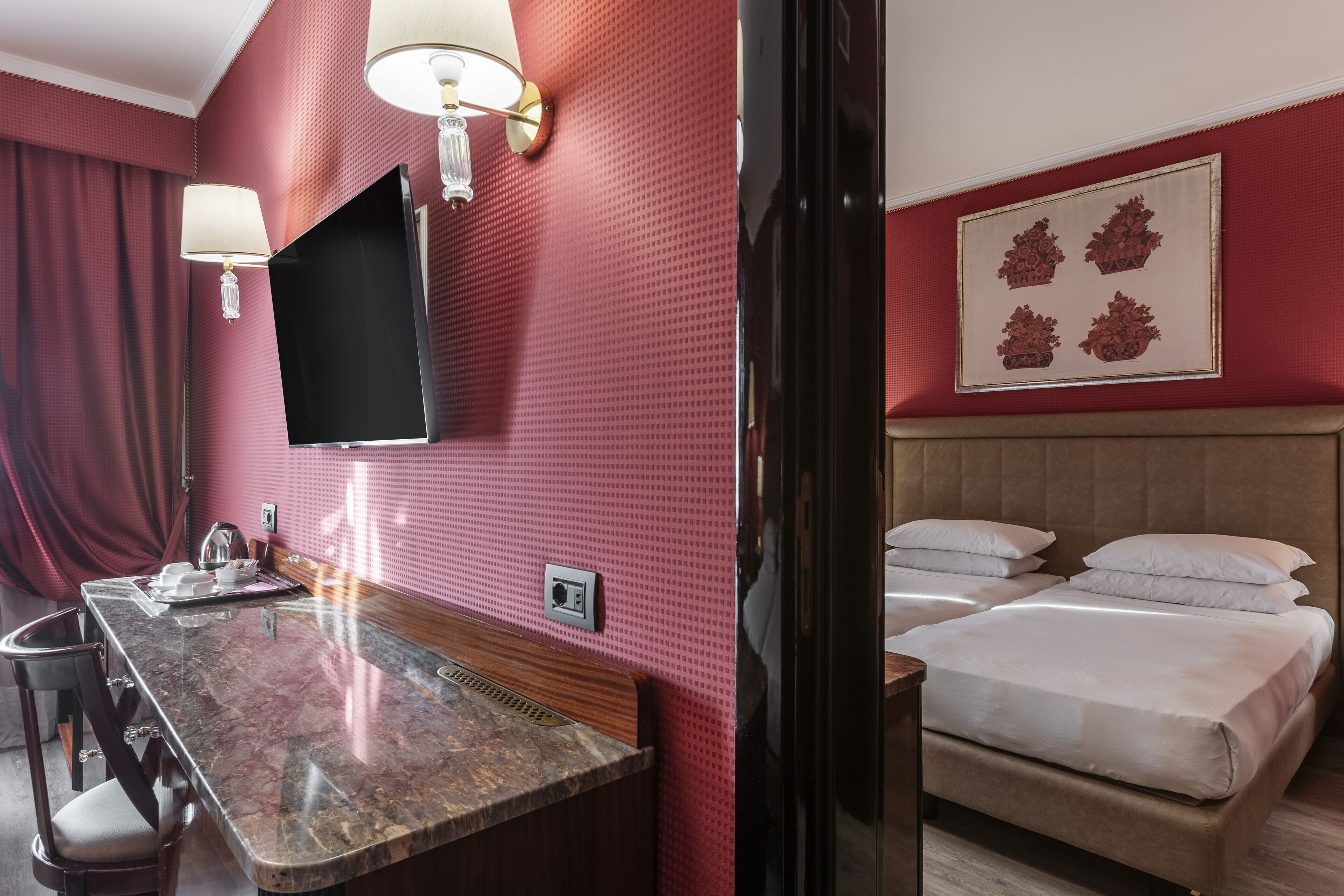 Habitación de hotel con encimera de mármol, televisor de pantalla plana montado en la pared, cama con ropa blanca y un adorno en la pared.