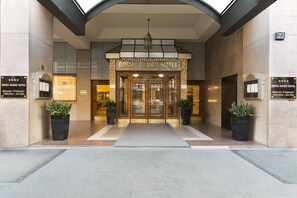 Indgangen til Doria Grand Hotel med dobbelte døre, krukker med planter og et skilt.