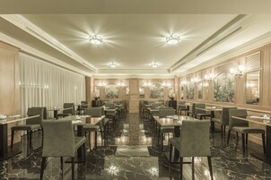 Un'ampia sala ristorante con pavimento in marmo lucido, diversi tavoli e sedie.