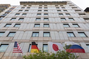Un edificio alto con numerosas ventanas y banderas de Estados Unidos, Alemania, Rusia y Japón.