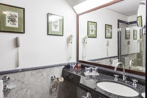 A bathroom with a marble sink, a large mirror, and framed floral artwork on the wall.