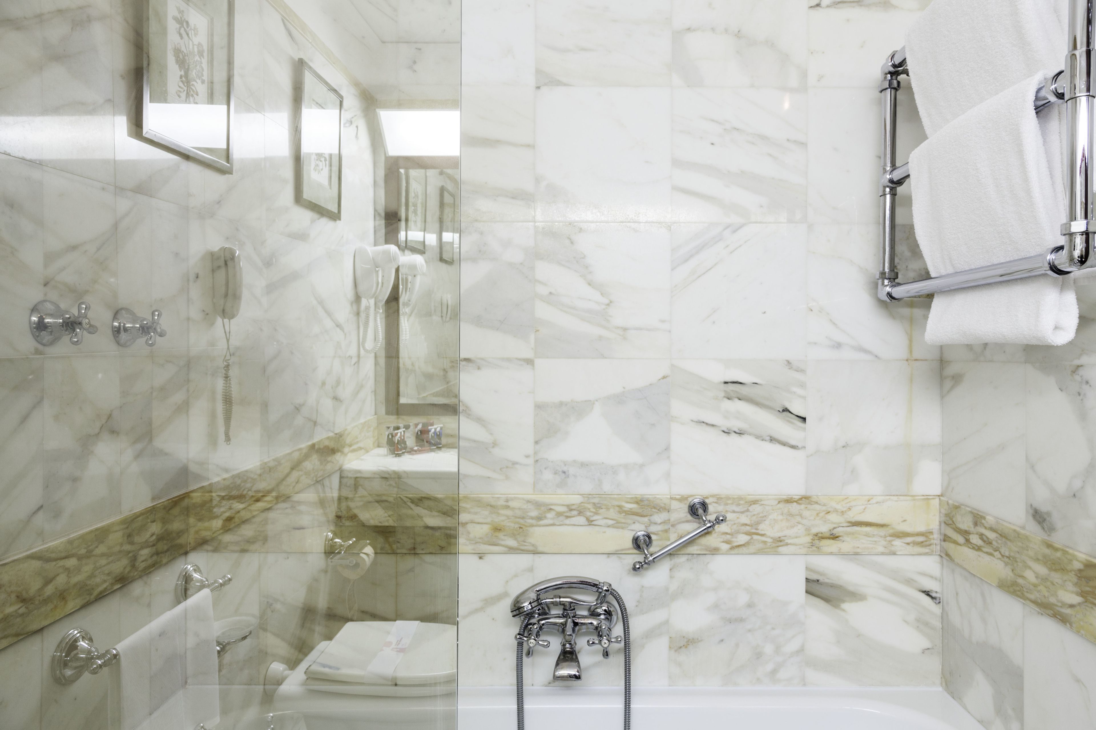 Une salle de bain avec des murs en marbre, une baignoire, des toilettes et une douche.