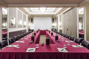 A conference room with a long table, chairs, and a projector screen.