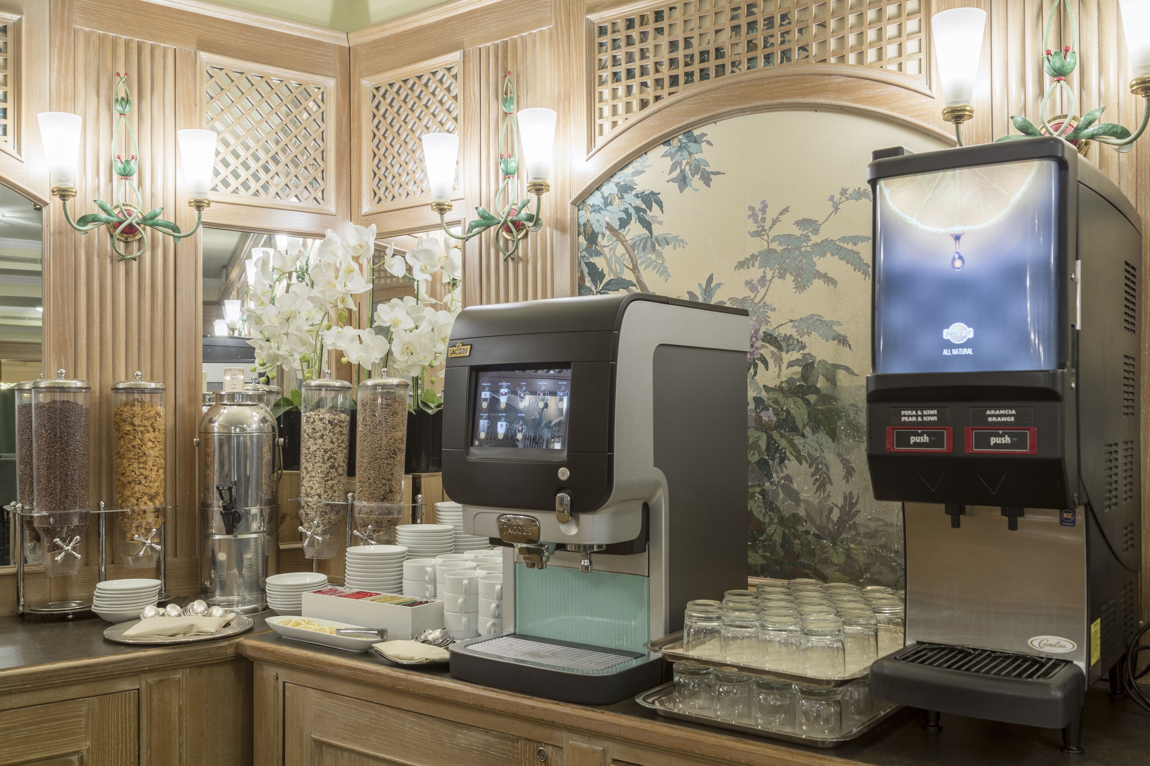 A coffee station with a coffee machine, a tea dispenser, and various containers of coffee and tea.