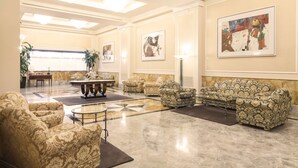A spacious lobby with patterned sofas, a coffee table, and artwork on the walls. - Doria Grand Hotel (Milan)
