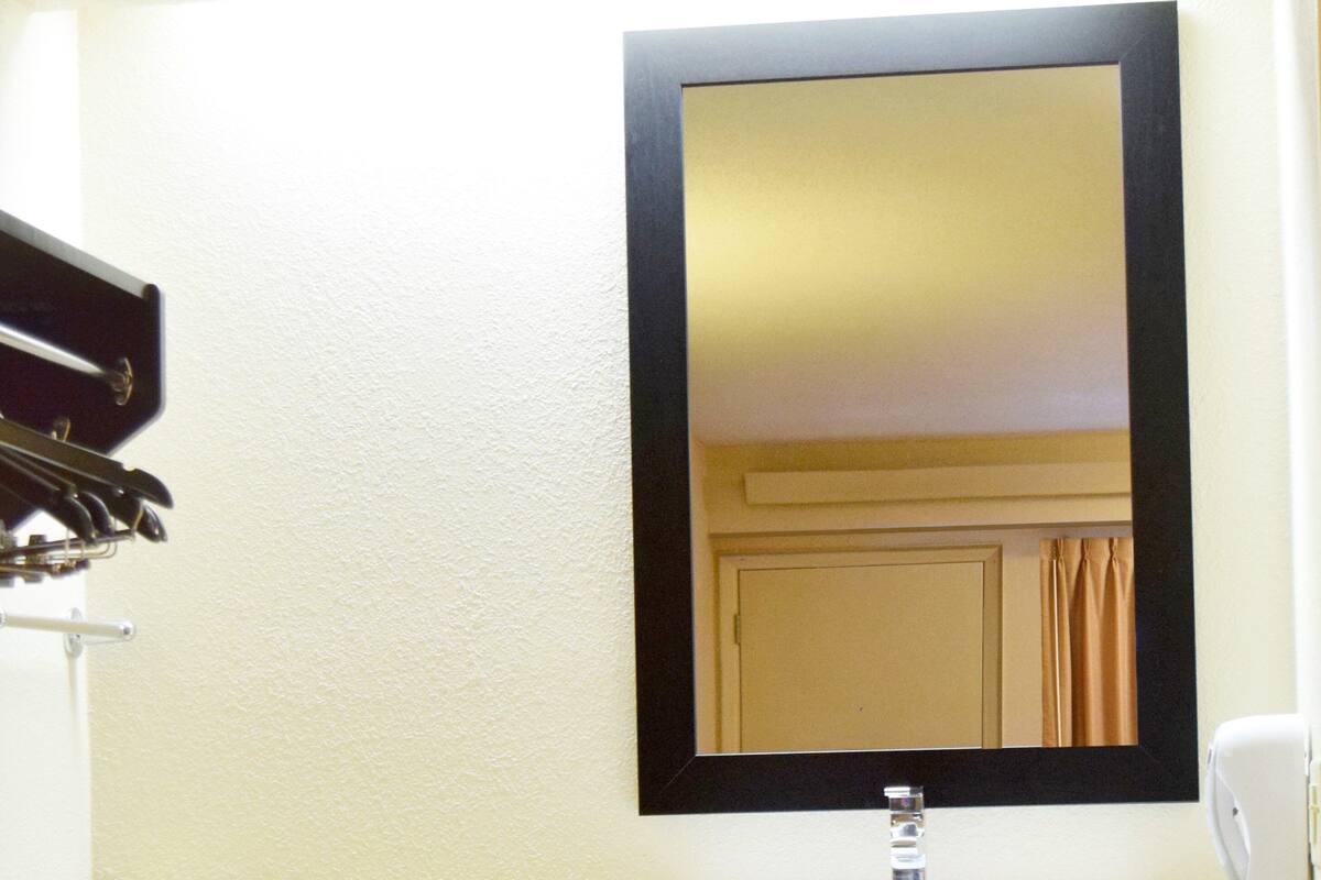 Een hotelbadkamer met een wastafel, spiegel, handdoekhouder en een zeepdispenser.