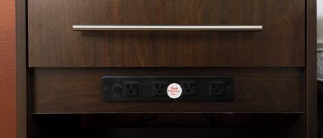 Un mueble de madera con un cajón y una regleta con botón de encendido.