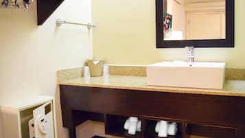 A bathroom with a white sink, a mirror, a towel rack, and a towel storage shelf.