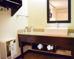 A bathroom with a white sink, a mirror, a towel rack, and a towel storage shelf.