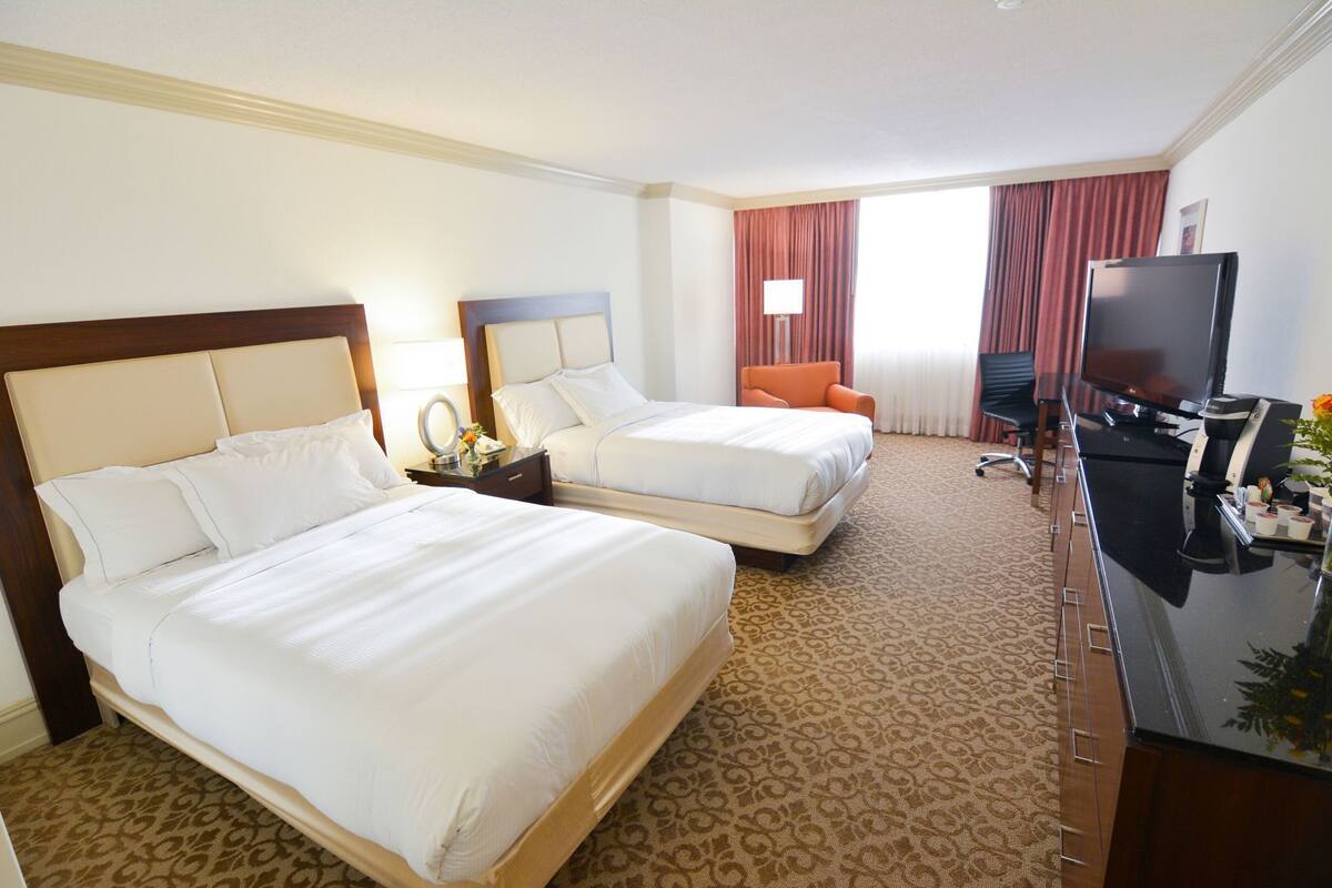 Une chambre d’hôtel avec deux lits, un bureau avec une télévision, une chaise et une machine à café.