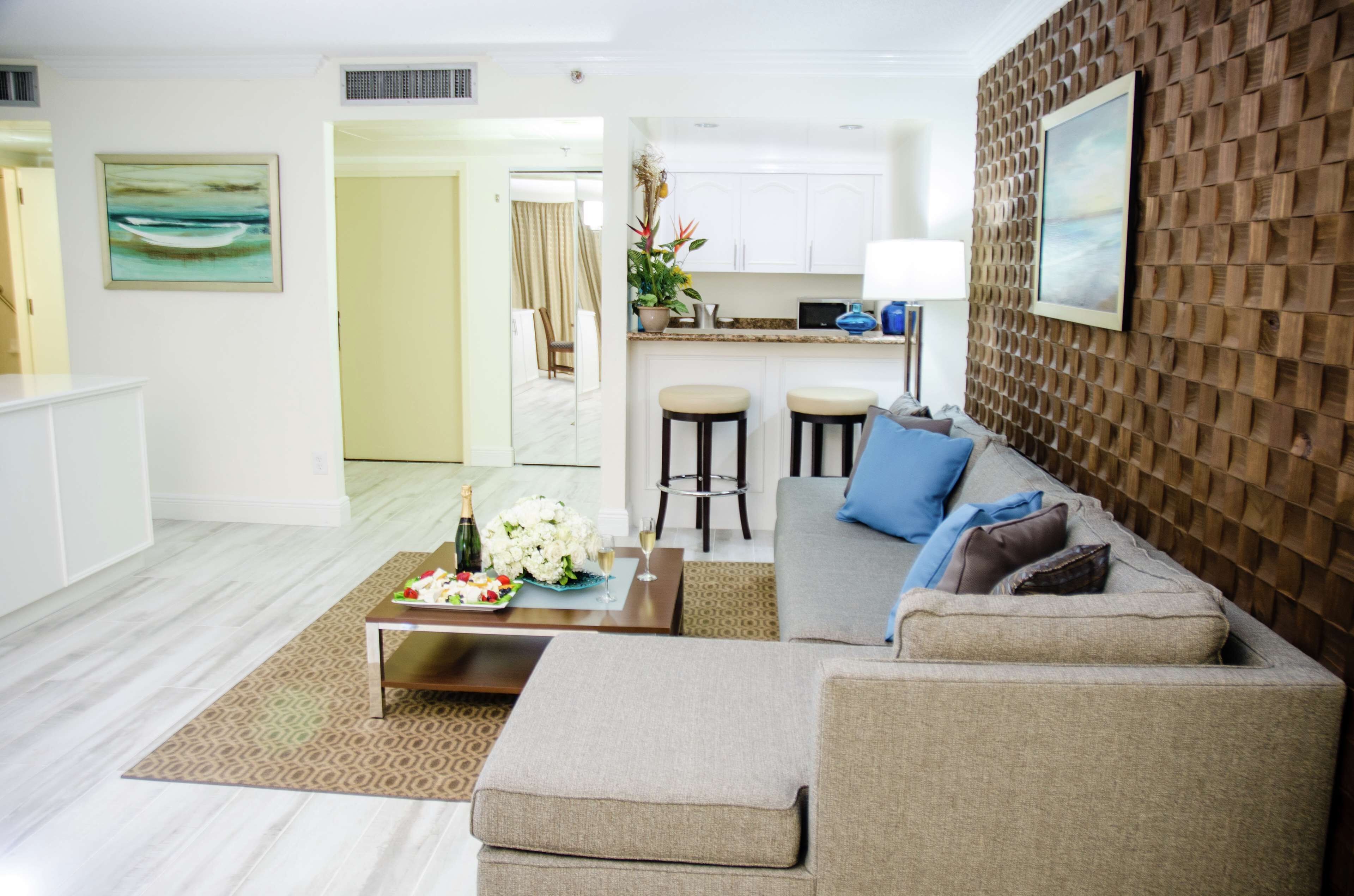 A modern living room with a sofa, coffee table, and a dining area with stools.