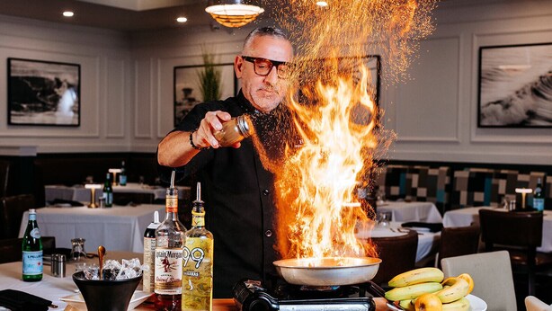 Un chef realiza una flambé con una botella de ron Captain Morgan 99, una botella de ron especiado y una sartén sobre una estufa.
