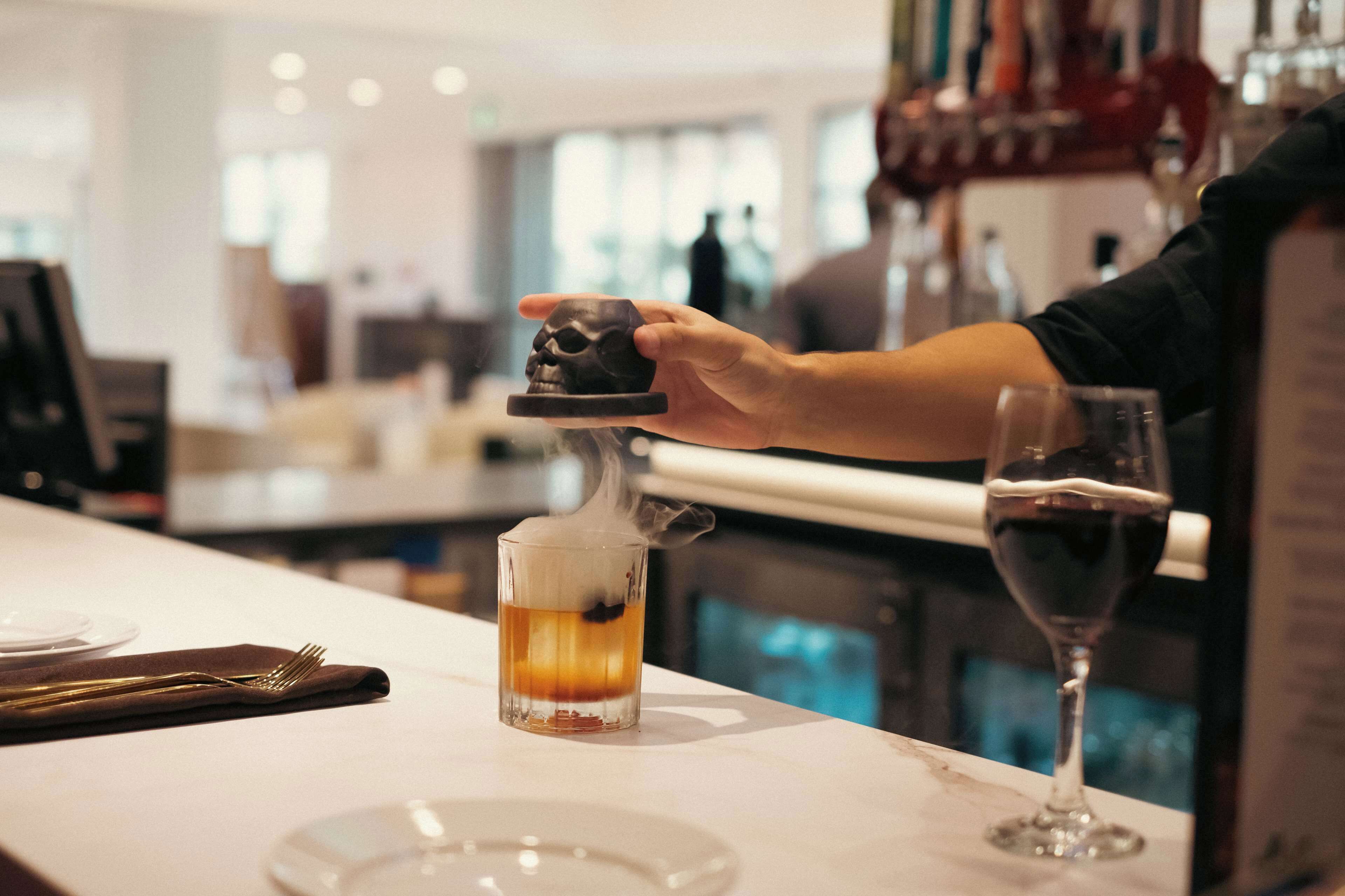 Une personne verse une boisson d’un récipient en forme de crâne dans un verre.