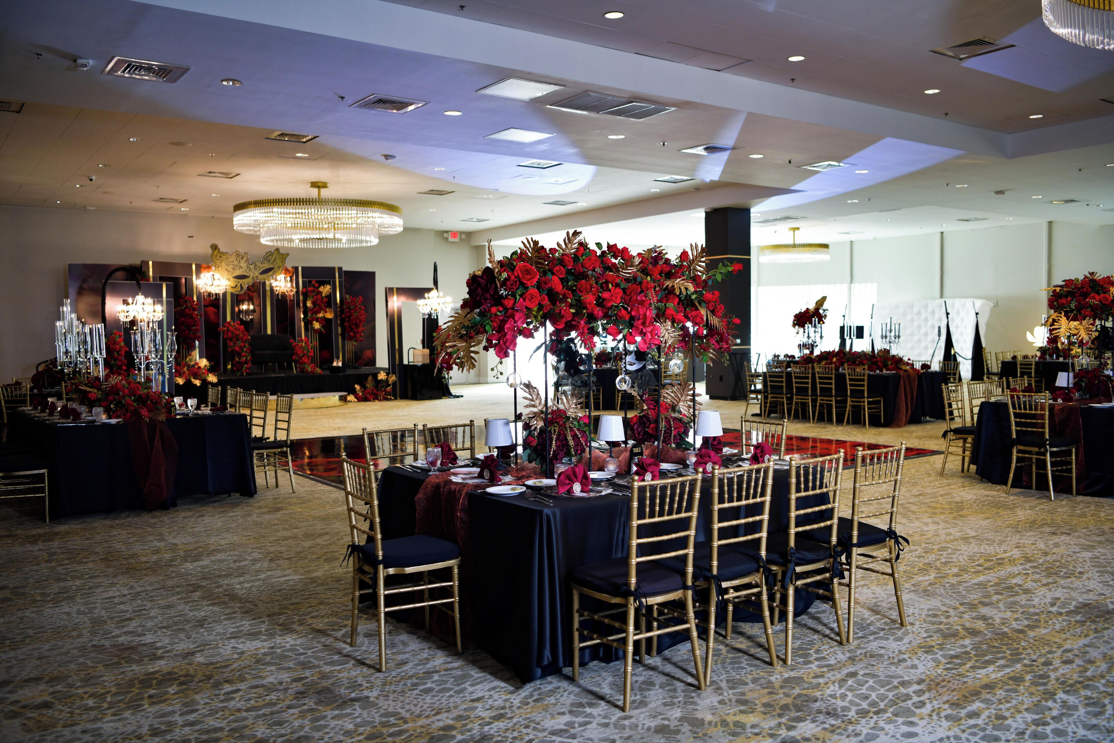 Une salle de banquet avec des tables rondes, des chaises et des centres de table floraux.