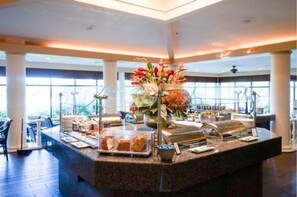 A breakfast bar with a variety of food items and a centerpiece of flowers. - Hilton Palm Beach PBI (West Palm Beach)