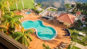 Un resort con una gran piscina, asientos al aire libre y palmeras.