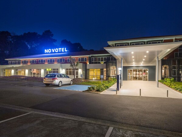 A hotel with a modern design, a parking lot, and a car parked in front.