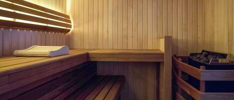 A sauna with wooden benches and a bench with a towel.