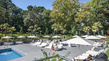 Una piscina al aire libre de temporada, sombrillas, tumbonas