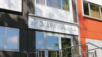 Un edificio con un letrero que dice 'O'SPA Institut & Fitness' y ventanas grandes.