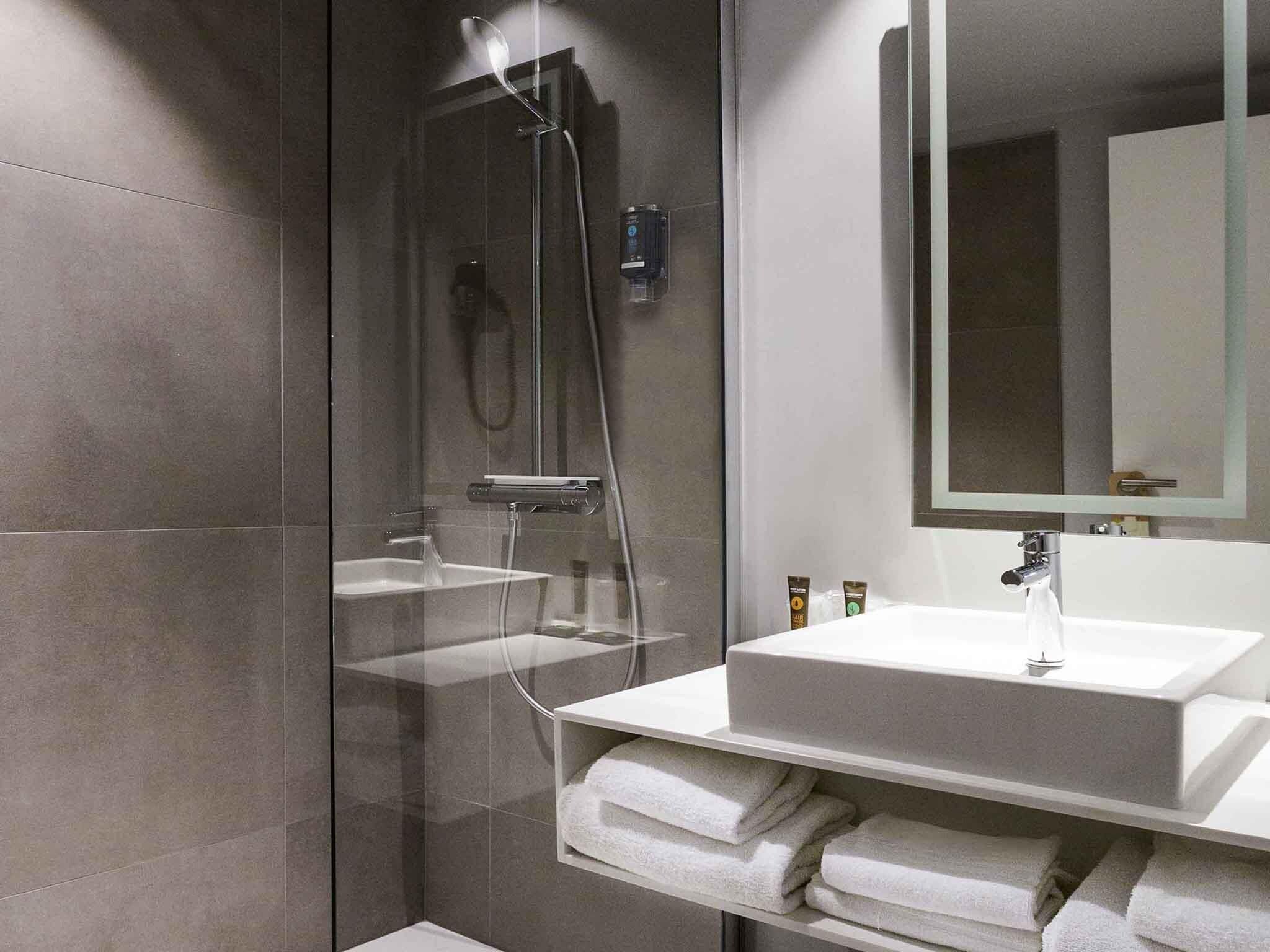 Ein modernes Badezimmer mit einer Duschkabine, einem weißen Waschbecken und einem Spiegel darüber.