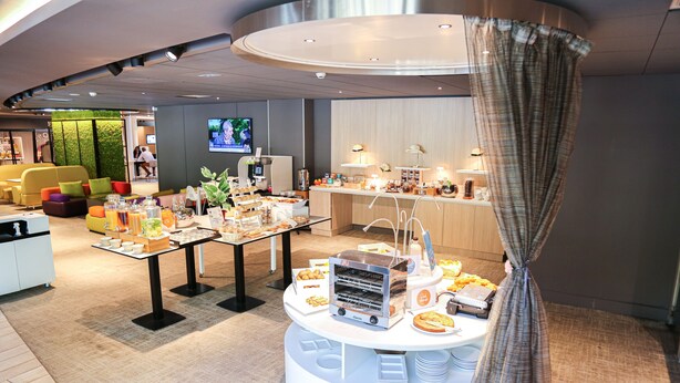 A modern hotel lobby with a buffet area, seating, and a television screen. - Novotel Resort & Spa Biarritz Anglet (Anglet)