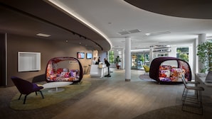 A modern lobby with a curved ceiling, a reception desk, and colorful seating areas. - Novotel Resort & Spa Biarritz Anglet (Anglet)