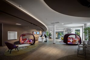 A modern lobby with a curved ceiling, a reception desk, and colorful seating areas. - Novotel Resort & Spa Biarritz Anglet (Anglet)