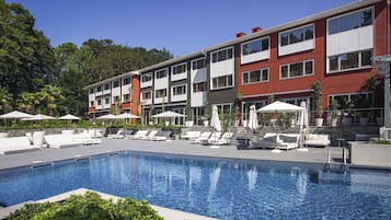 Una piscina al aire libre de temporada, sombrillas