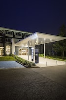 A modern building with a covered entrance, a sign for 'NOVOTEL', and a wheelchair accessibility symbol.