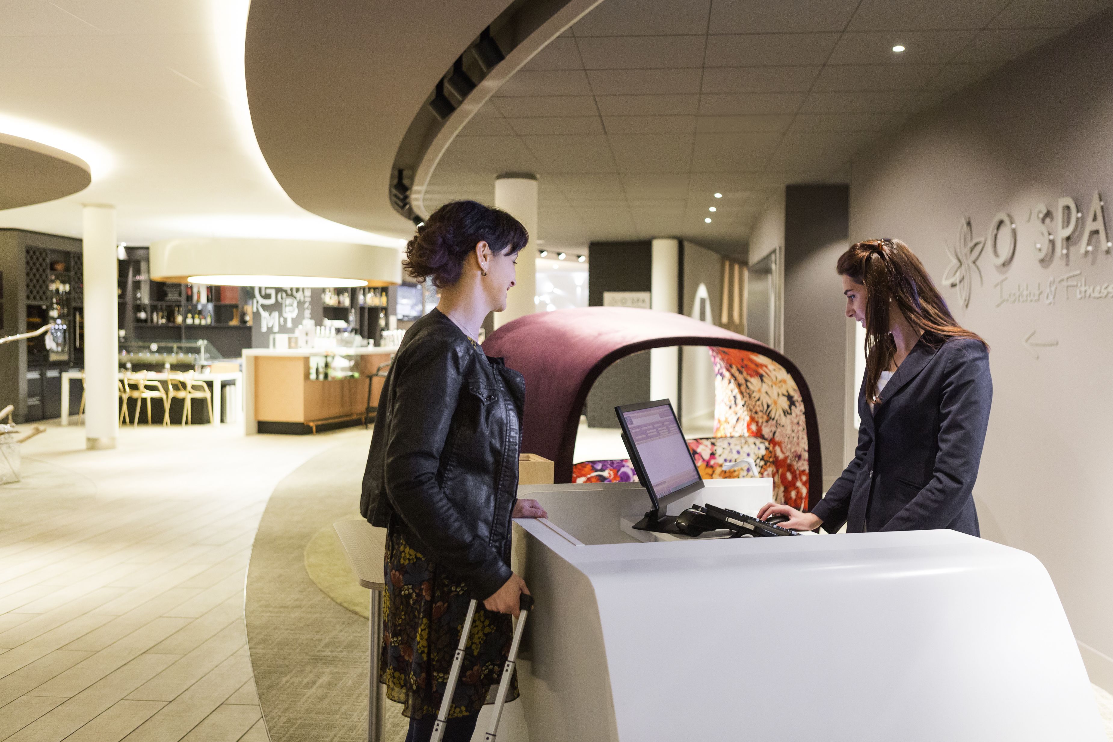 A reception area with a counter, a computer, and a wall with a spa sign.