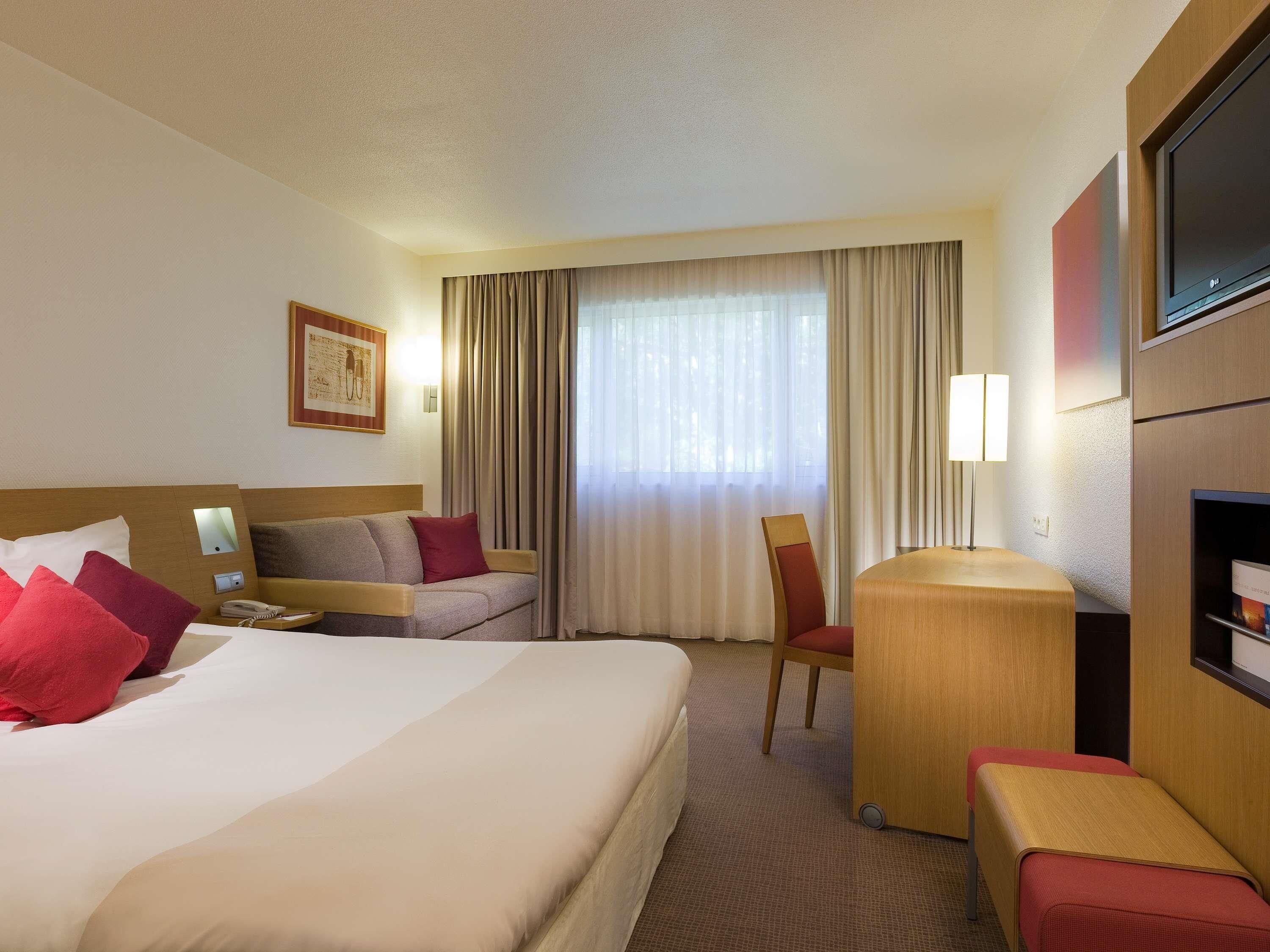 Een hotelkamer met een groot bed, een bank, een bureau, een stoel en een televisie.