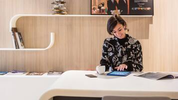 A person seated at a table with a tablet, a cup, and a smartphone.