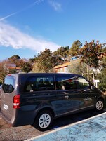 Una camioneta negra de Novotel estacionada en un estacionamiento, con un cielo azul despejado y árboles al fondo.