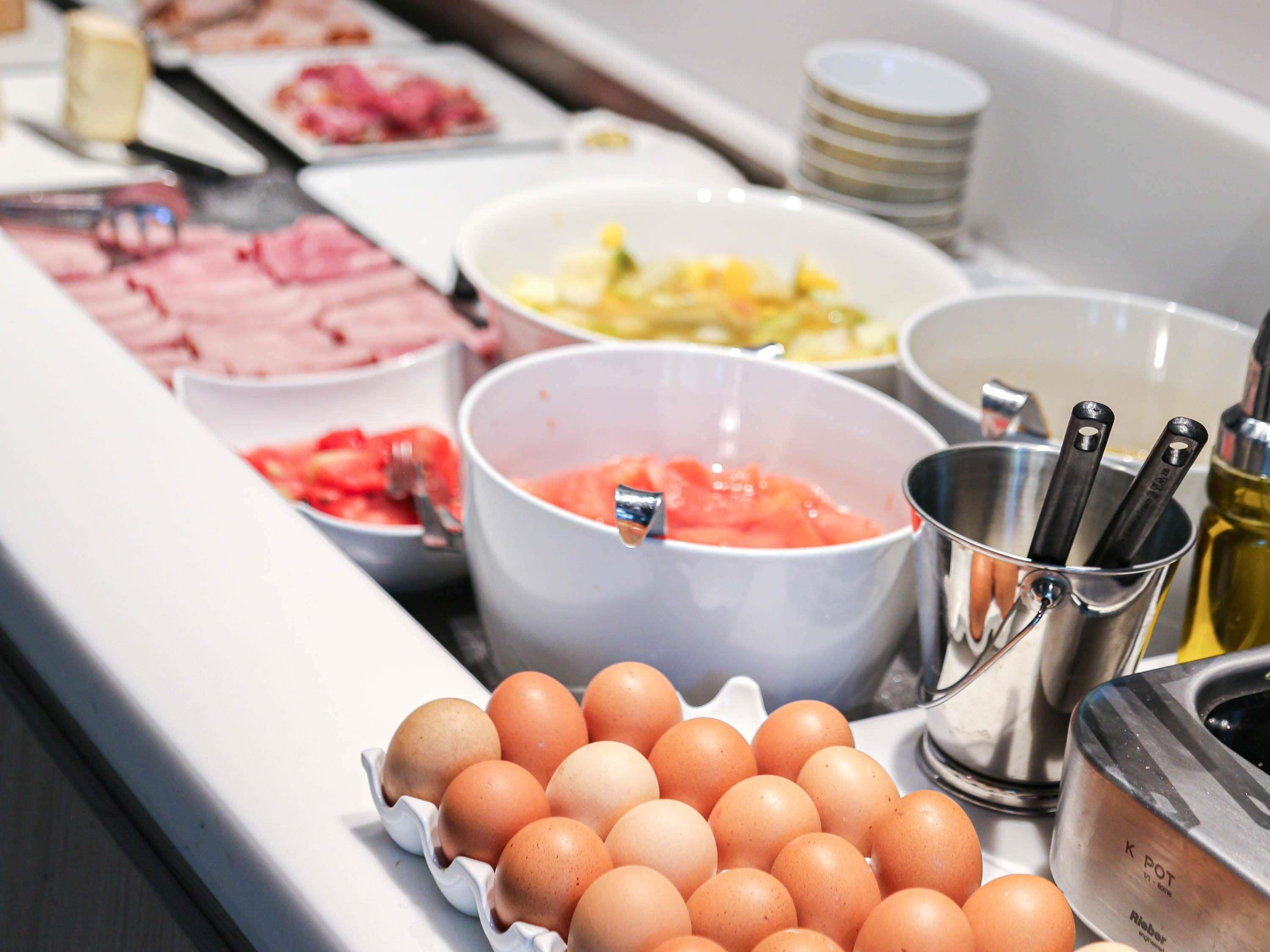 A buffet with various food options including eggs, fruits, and meats.