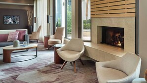 A modern living room with a fireplace, comfortable seating, and a large window offering a view of the outdoors. - Courtyard by Marriott Tallahassee Downtown/Capitol (Tallahassee)