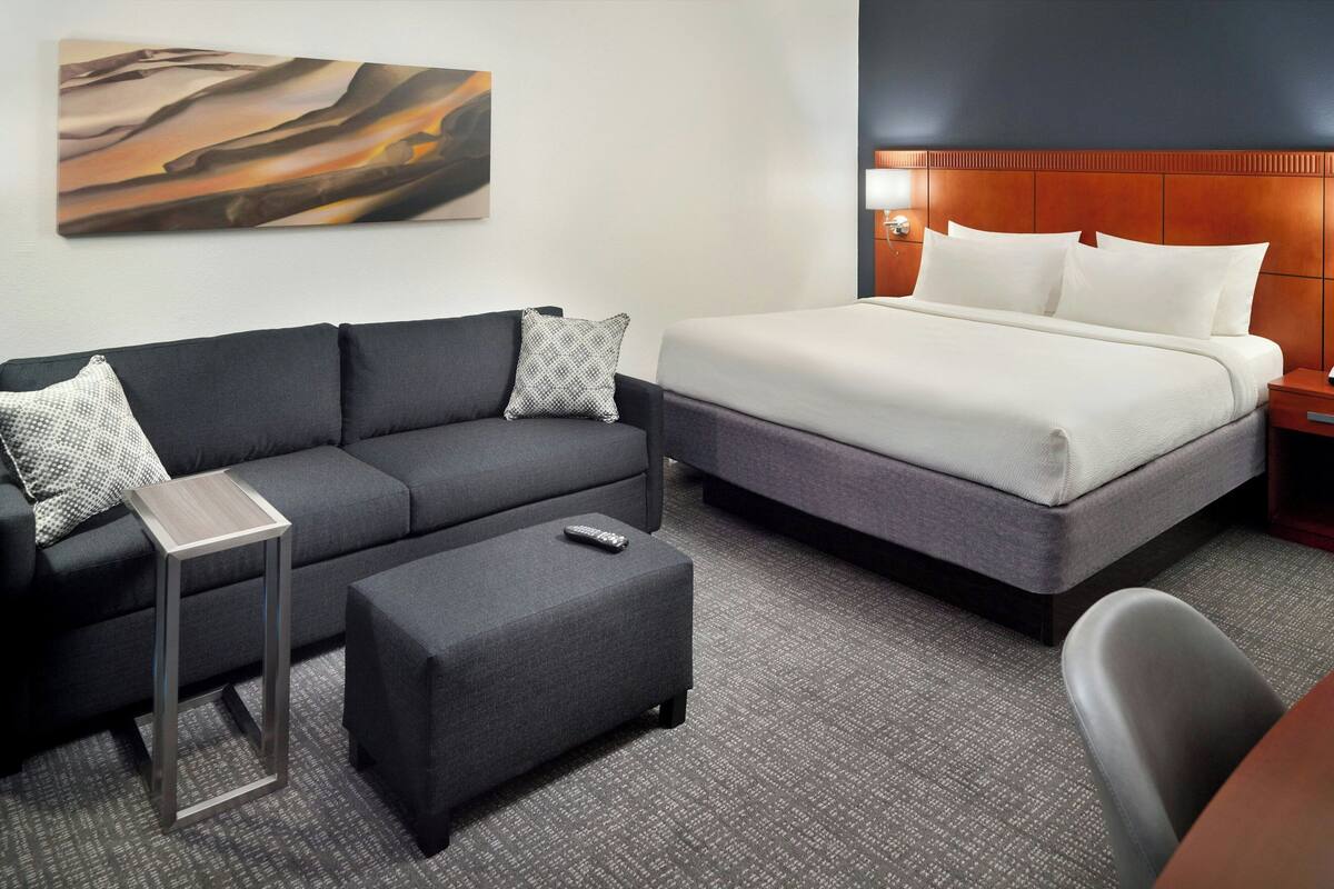 Een hotelkamer met een bed, een bank, een bijzettafeltje en een stoel.
