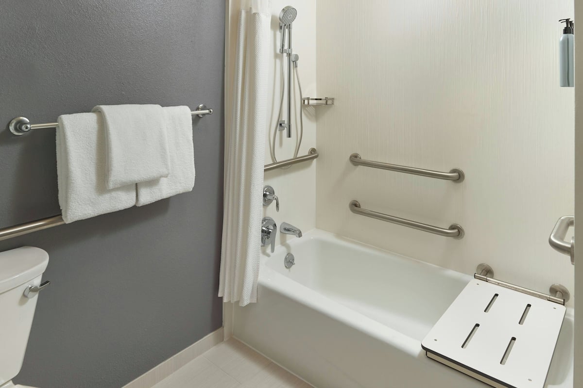 Een badkamer met een bad, handgrepen, een handdoekhouder en een toilet.