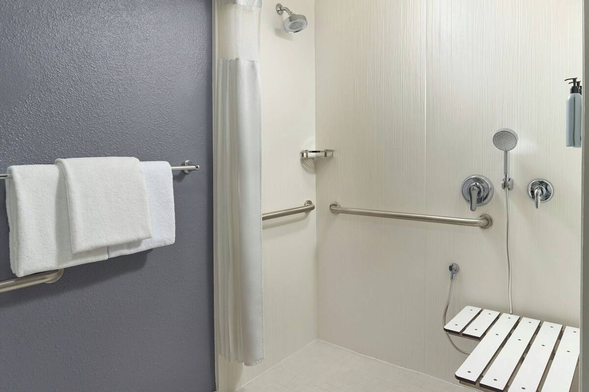 Een badkamer met een douche, een handdoekhouder en een handgreep.