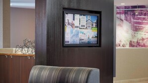 A hotel reception area with a modern design, featuring a large digital display on the wall, a reception desk, and a seating area with a sofa. - Courtyard by Marriott Tallahassee Downtown/Capitol (Tallahassee)